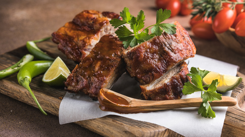 Cut ribs on a board with limes, peppers, and parsley