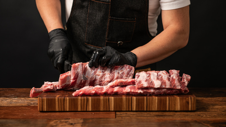 Man cutting ribs on a wooden board