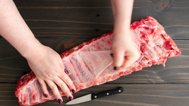 Hands of a woman pulling the membrane from ribs