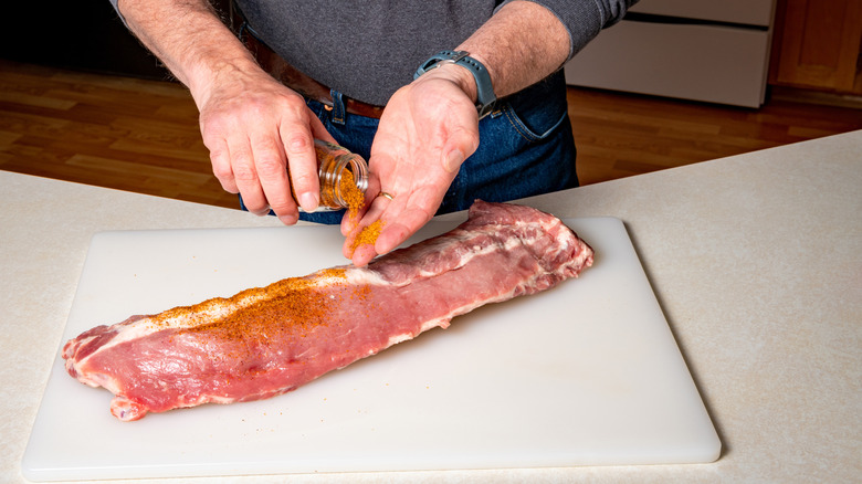 Man pouring seasoning into his hand to rub on ribs