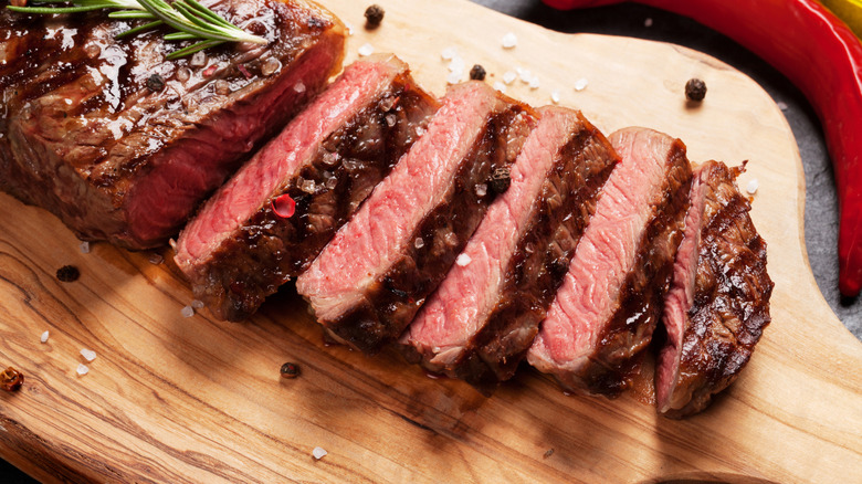 Sliced steak showing the medium doneness on a wood board