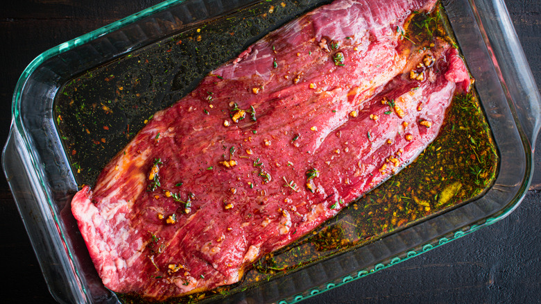 Flank steak marinating in a glass dish