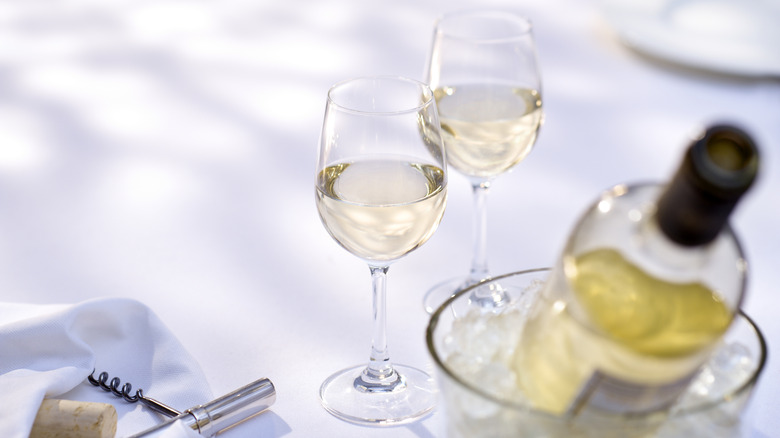 Two glasses of white wine and bottle of white wine in ice bucket