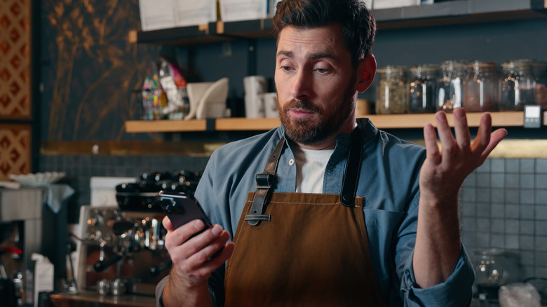Restaurant employee on phone, shrugging
