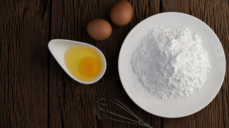 Egg and flour in bowls with a whisk
