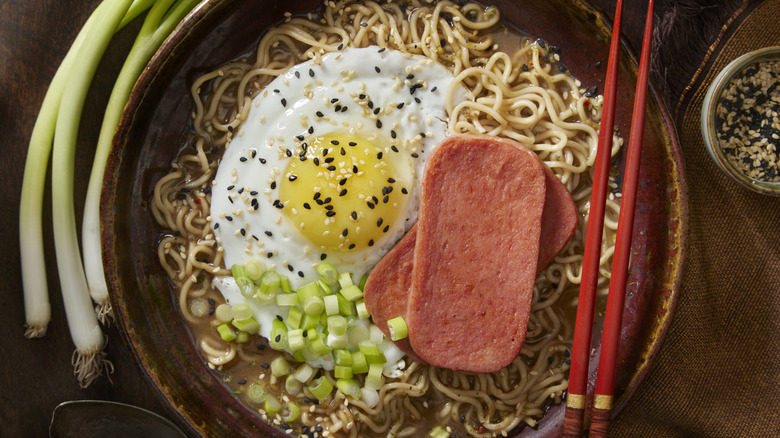 A bowl of ramen topped with Spam, a fried egg, and scallions