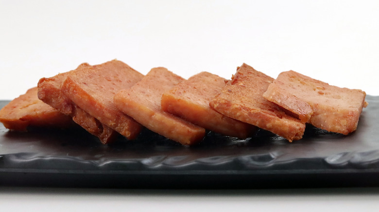 Slices of Spam on a black plate