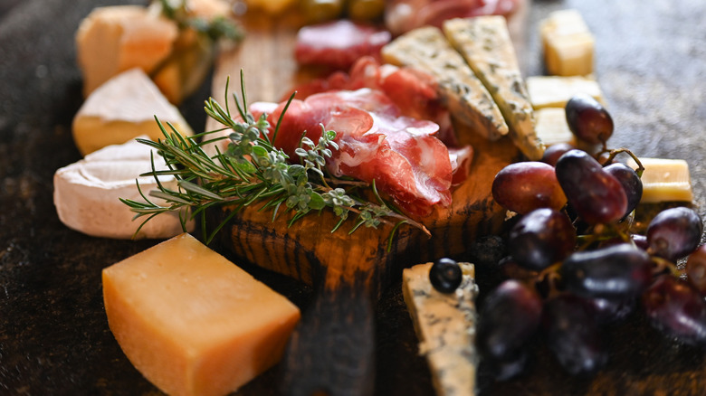 A charcuterie board with meats, cheeses, and grapes