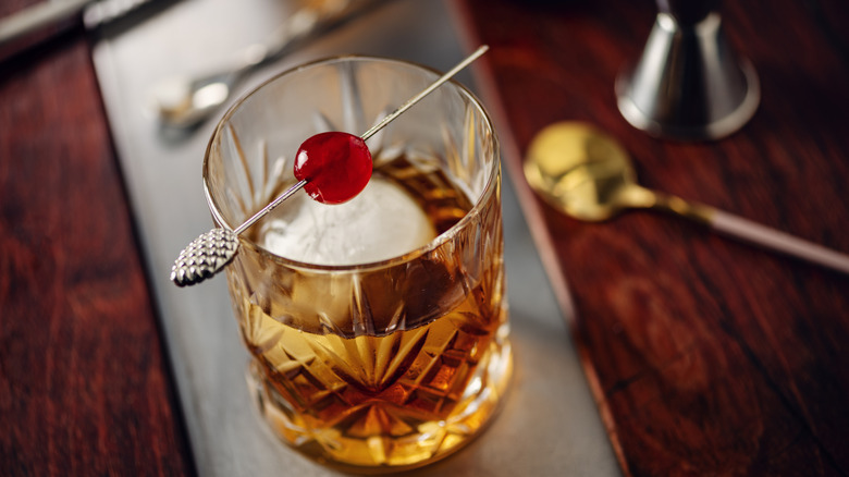 A Manhattan cocktail with bright red maraschino cherry