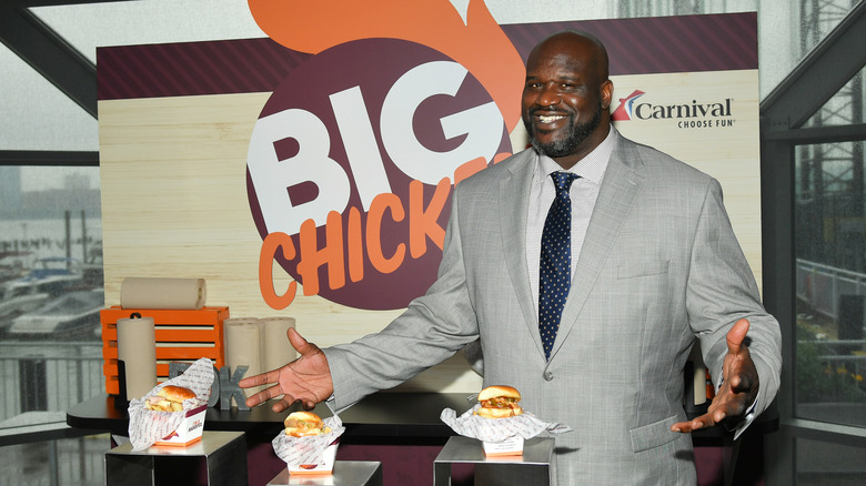 Shaq posing with three Big Chicken sandwiches
