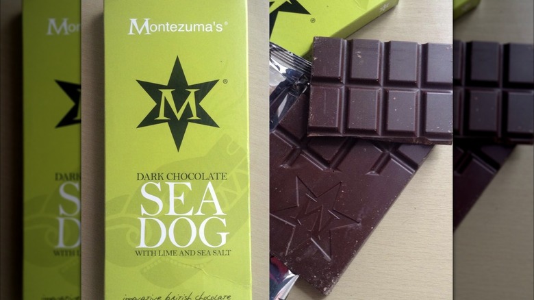 Bar of Montezuma's Sea Dog chocolate bar with lime and sea salt in paper wrapper next to the chocolate bar