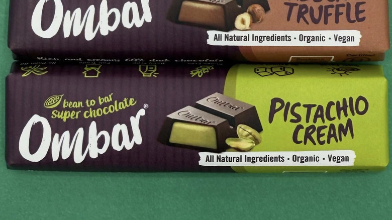 Ombar Pistachio Cream and Ombar Hazelnut Truffle bars in paper wrappers on green background