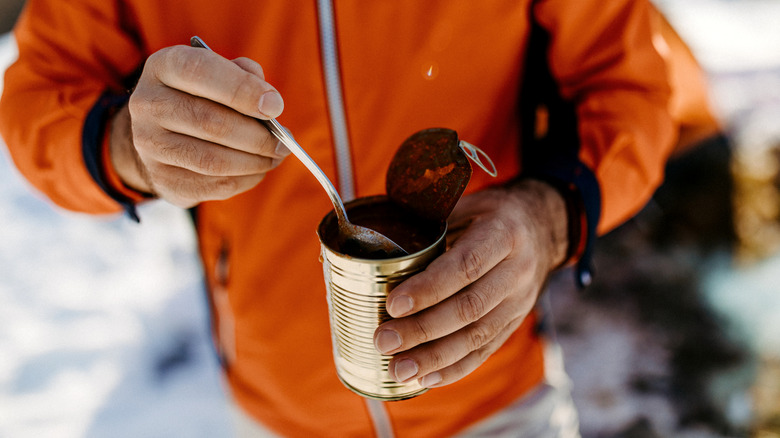 Hiker eating soup from can