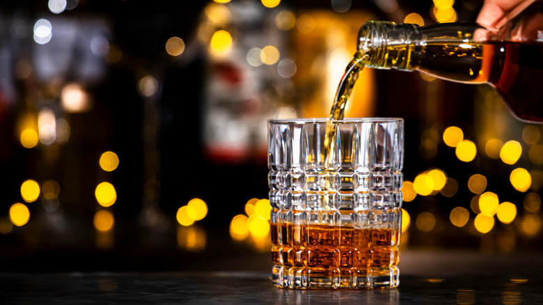 Whiskey being poured into glass on bartop