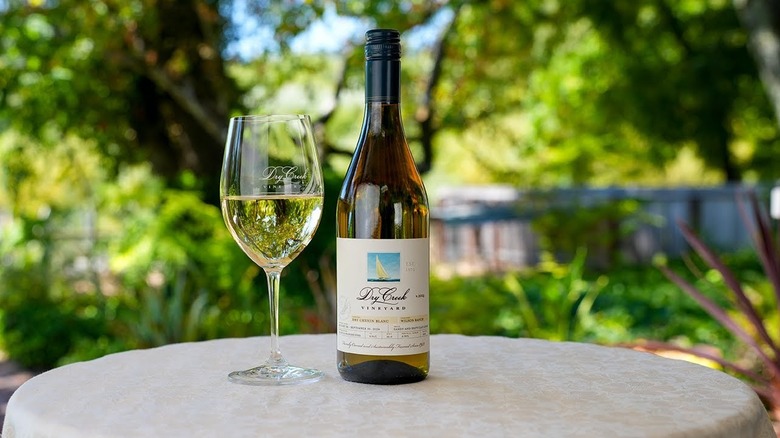Dry Creek bottle of wine and glass set outside on a white patio table