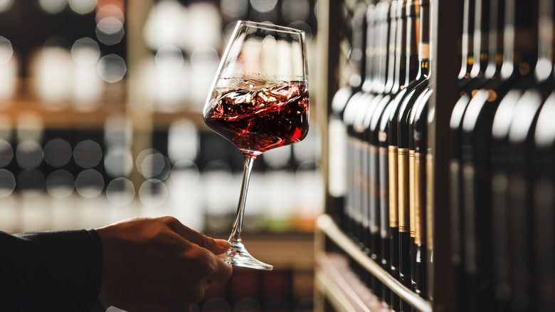 A person's hand swirling a glass of red wine
