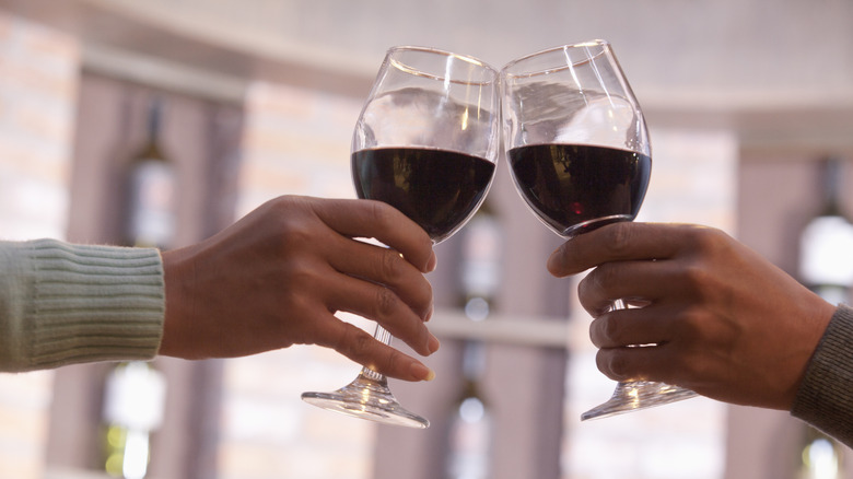 Two hands toasting with glasses of red wine