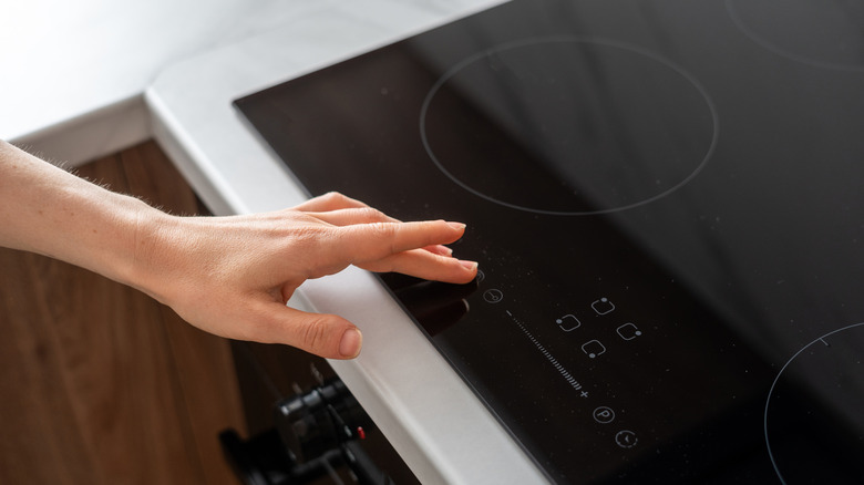 Hand adjusting temperature on induction stove