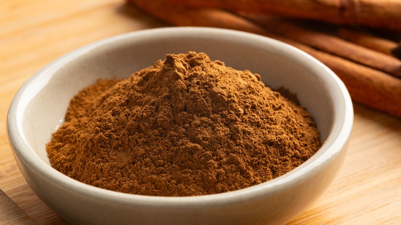 Bowl of cinnamon with cinnamon sticks background