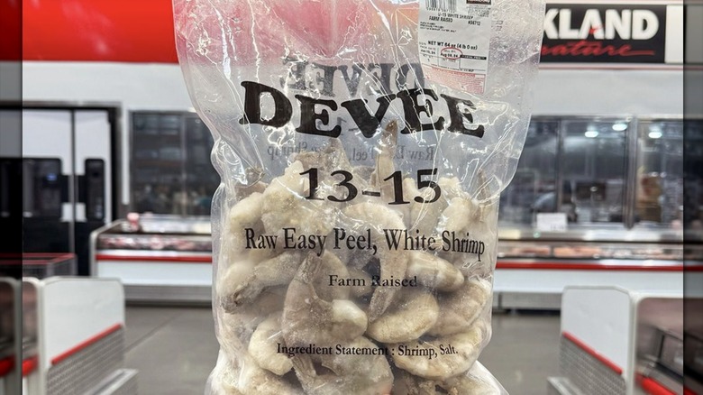 Hand holding bag of frozen raw shrimp