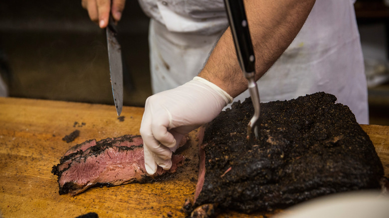 Deli employee slices pastrami
