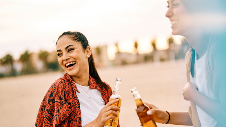 Two women drinking beer on beach