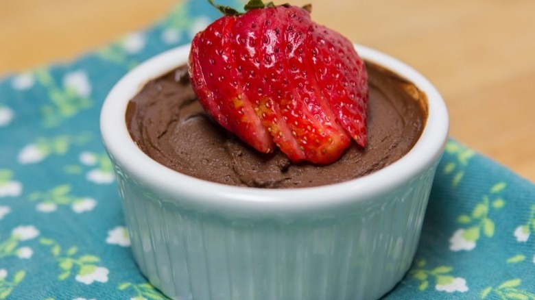 Chocolate mousse in ramekin topped with sliced strawberry