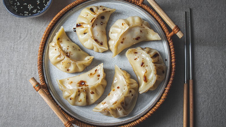 Gyoza on a plate with a splash of soy sauce.