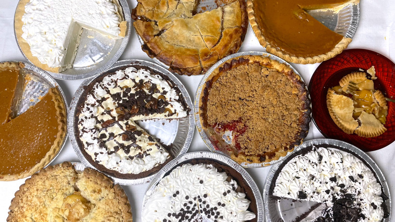 A collection of whole grocery store frozen pies with slices taken out of them, tasted side-by-side