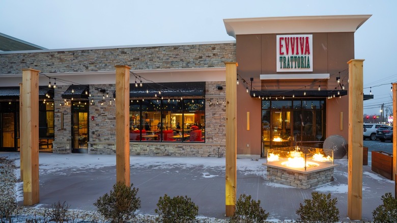 Outdoor seating area of Evviva Trattoria  in Bedford, New Hampshire, empty patio with a little snow and a flaming fire pit