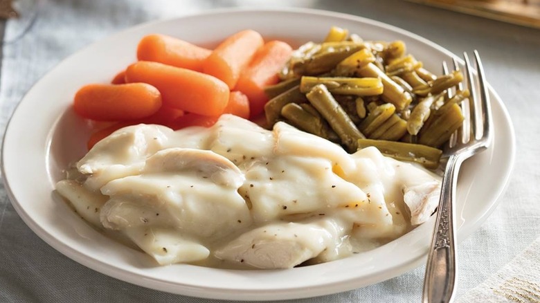 A plate of chicken n' dumplins with carrots and green beans