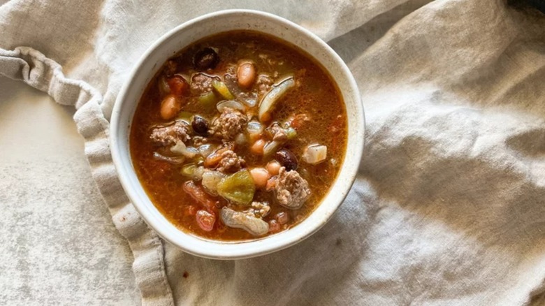 Aerial photo of a bowl of bison chili on top of a beige linen napkin