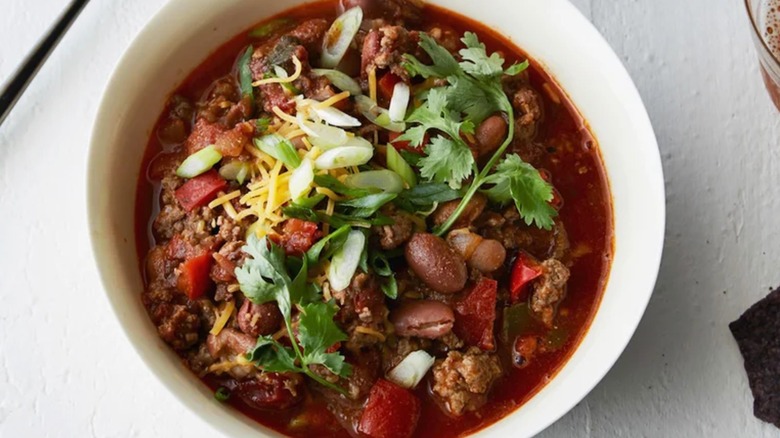 Aerial photo of a bowl of classic beef chili topped with green onions and cilantro