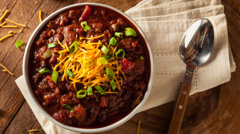 aerial photo of a bowl of chili with a linen napkin and spoon