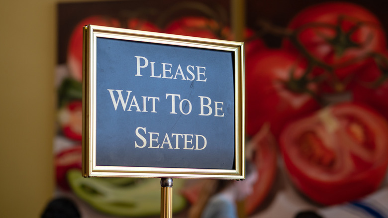 restaurant sign that reads "please wait to be seated"