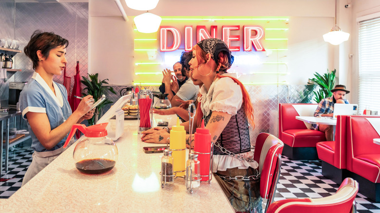 a server taking customer order at the counter of a retro-style diner