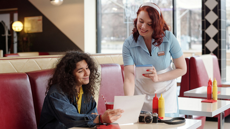 a woman ordering from a server in a retro-style diner