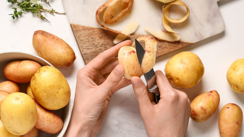 Hands peeling a bowl of potatoes