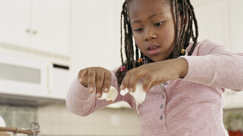 Child cracking an egg into a bowl