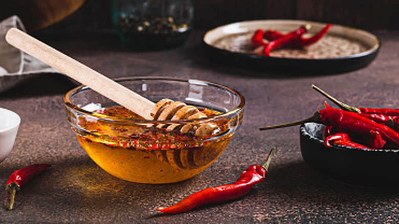 A bowl of honey surrounded by chillies