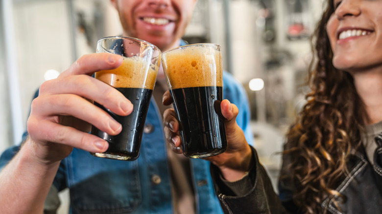 Two people toasting with glasses of stout