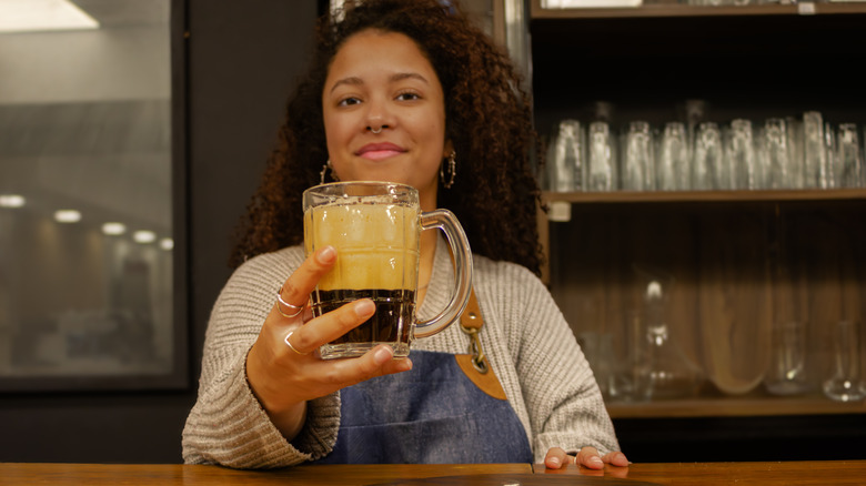 Woman holding out glass of stout