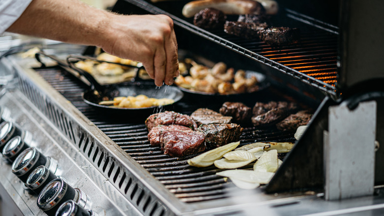 Chef's hand sprinkling salt with clear zones on grill
