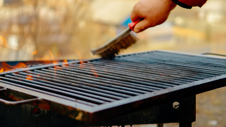 Person's hand with a grill brush cleaning the grill