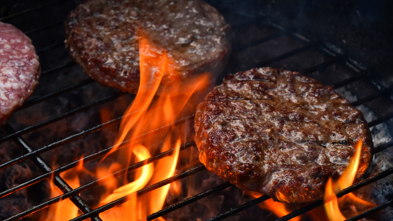 Flames flashing up onto burgers on grill