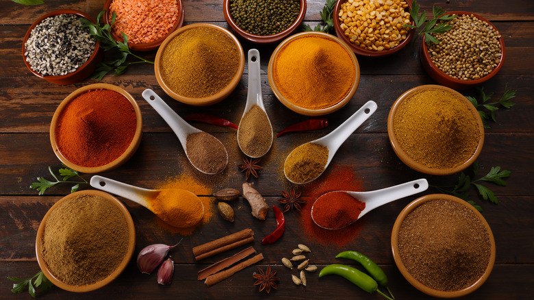 A variety of bowls of spices on a wooden table