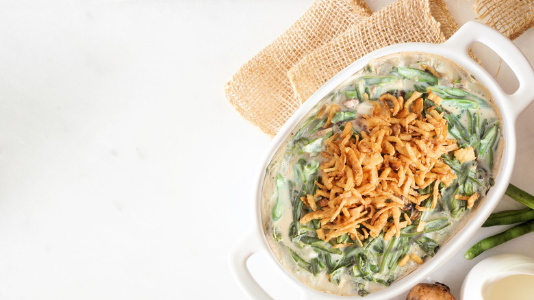 Green bean casserole in a white dish on top of burlap