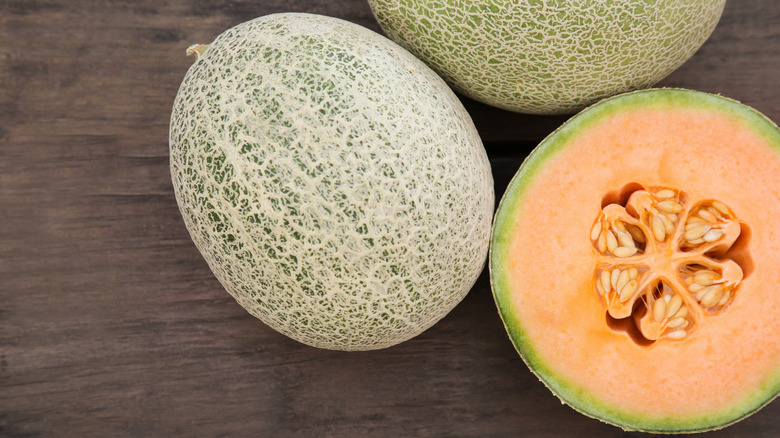whole and cut cantaloupes on wooden table