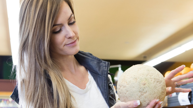 woman selecting cantaloupe