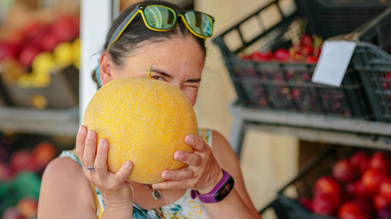 woman holding up ripe cantaloupe
